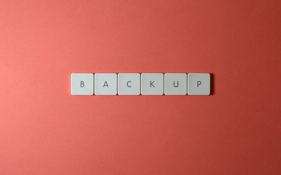 Free Close-up of keyboard keys spelling 'BACKUP' placed on a coral-colored surface. Stock Photo