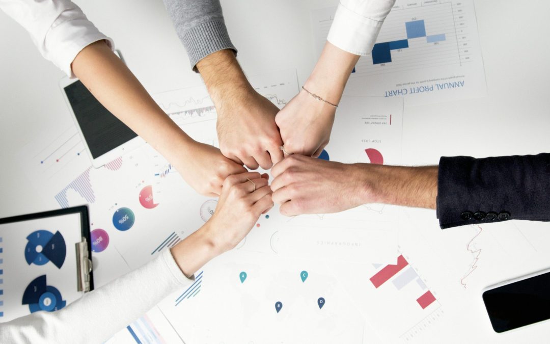 Free Colleagues celebrate success with a fist bump over financial charts depicting teamwork and unity. Stock Photo